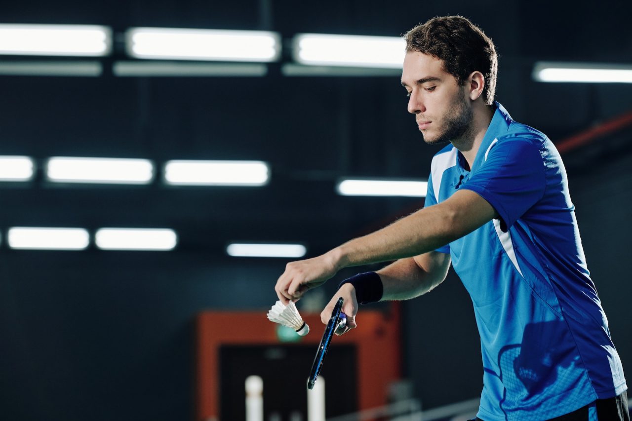 Badminton player serving shuttlecock